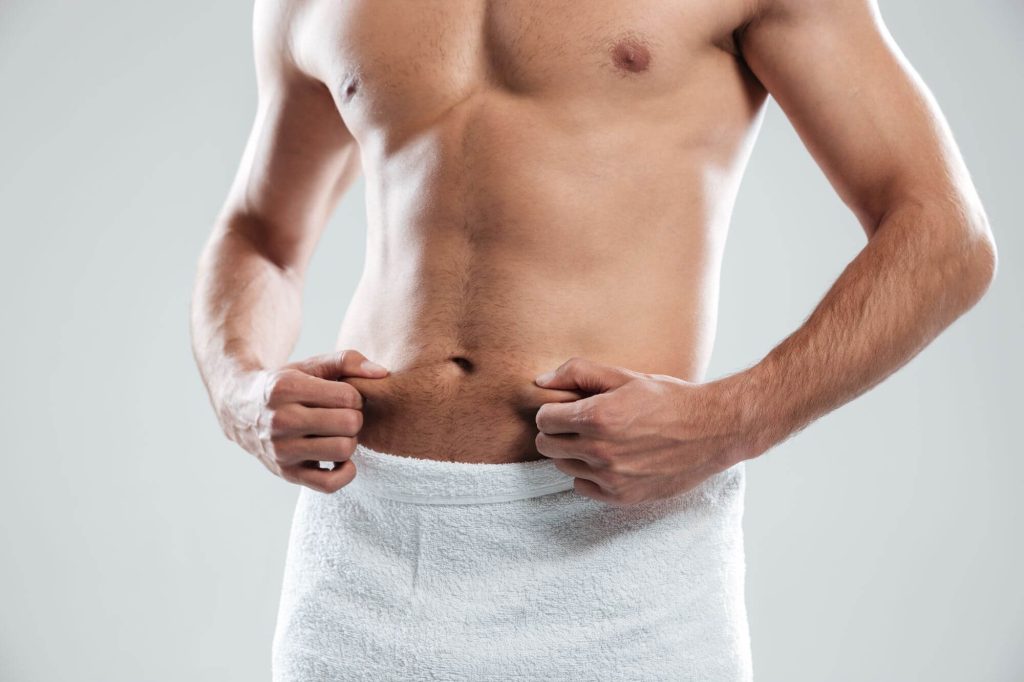 Hombre con el torso descubierto, tiene un abdomen firme, bonito y tonificado